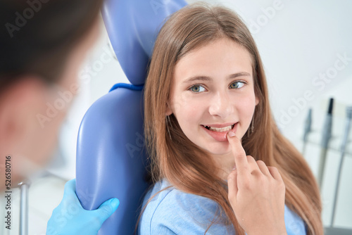 Calm teenage patient consulting professional pediatric dentist