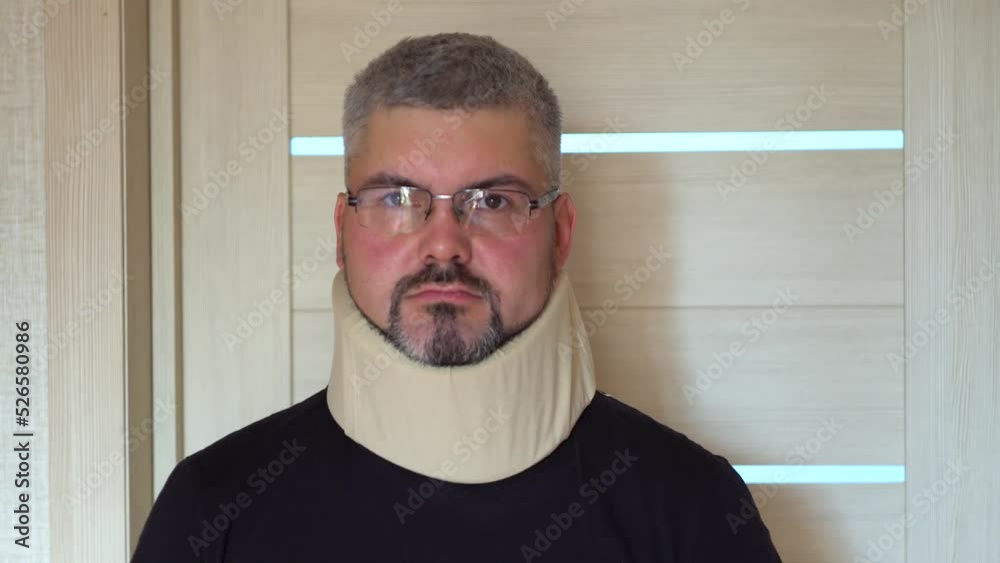 An older man is standing at the door. An orthopedic collar is worn on the neck. Spinal injury. Treatment of neck disease. Medical collar. Rehabilitation. An older man is standing at the door. An orthopedic collar is worn on the neck. Spinal injury. Treatment of neck disease. Medical collar. Rehabilitation.