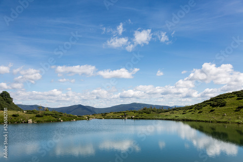 The water surface of a calm lake Vorozhesku against the background of the Gorgan mountain range © almostfuture