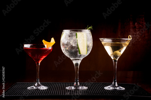 collection of three cocktail glasses including gin tonic martini and vesper with olive in rubber holder viewed from the front photo