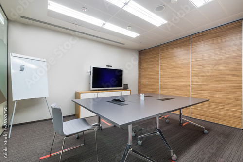 Office meeting room with light walls, gray carpet and furniture.