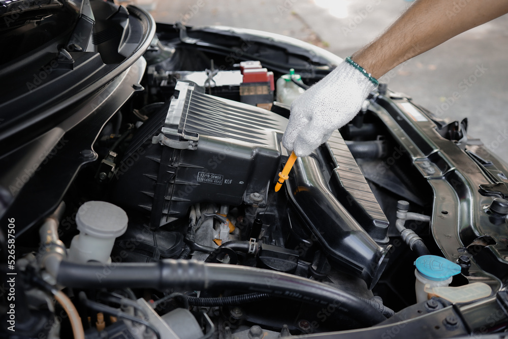 Close-up of a man's hand pulling a dipstick to check the engine oil level.
