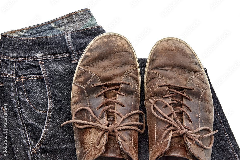 Stylishly distressed vintage brown leather shoes and black jeans isolated on white background