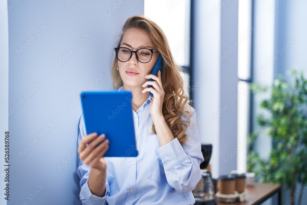 Young blonde woman business worker talking on the smartphone using touchpad at office Young blonde woman business worker talking on the smartphone using touchpad at office