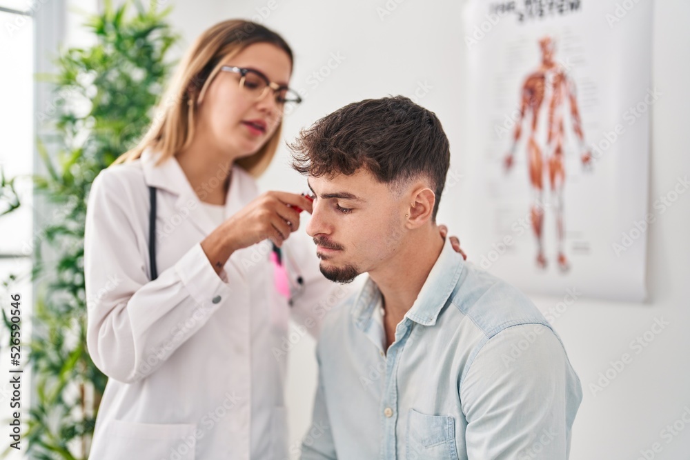 Young man and woman doctor and patient auscultating heart at clinic Young man and woman doctor and patient auscultating heart at clinic
