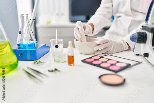 Young hispanic woman scientist making makeup working at laboratory
