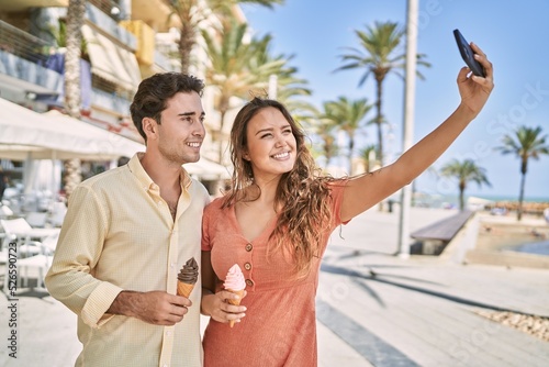 Man and woman couple eating ice cream and make selfie by the smartphone at seaside