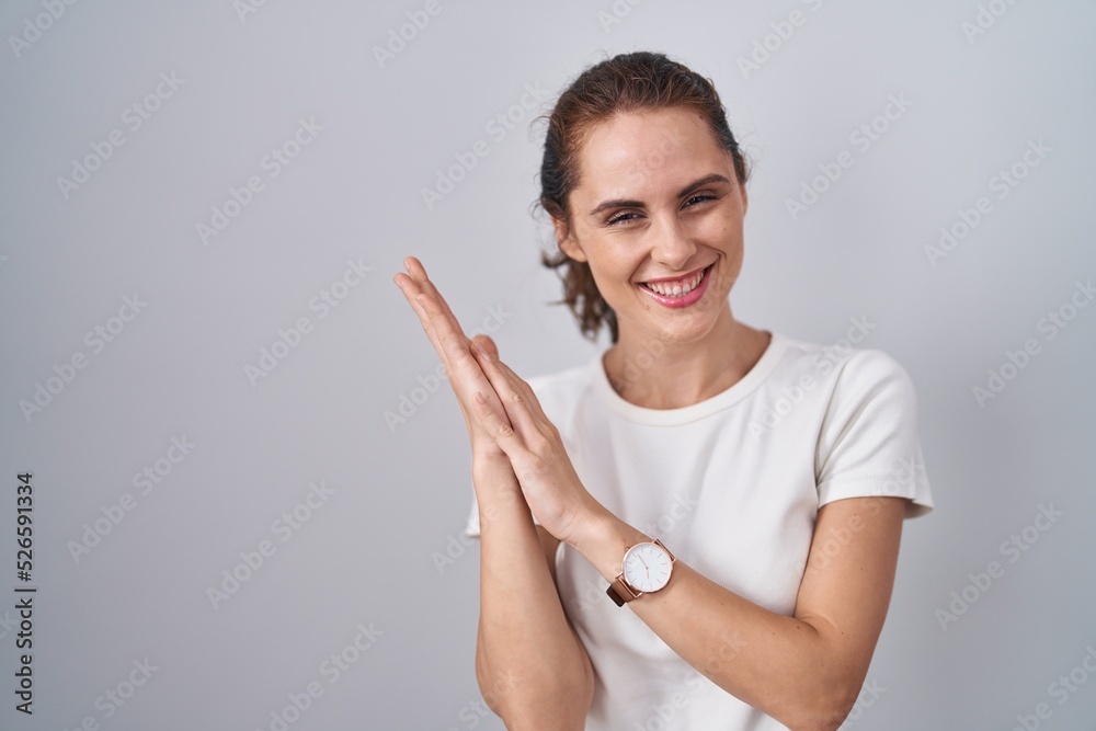 Fototapeta premium Beautiful brunette woman standing over isolated background clapping and applauding happy and joyful, smiling proud hands together