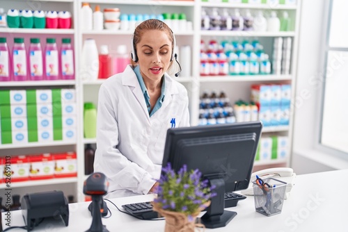 Young beautiful hispanic woman pharmacist operator having video call at pharmacy