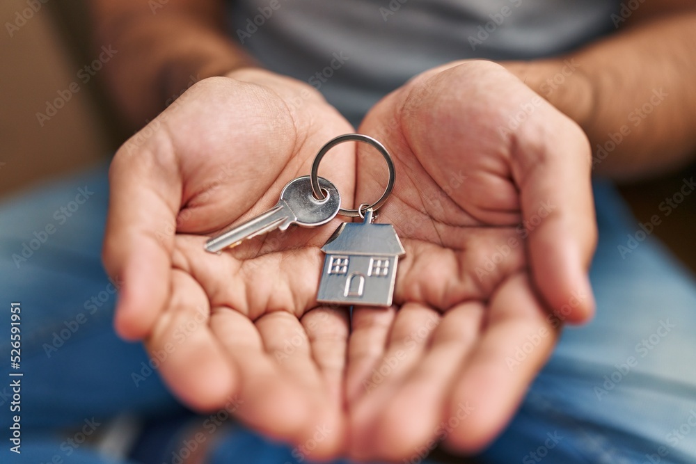Young hispanic man holding key of new house at new home Young hispanic man holding key of new house at new home