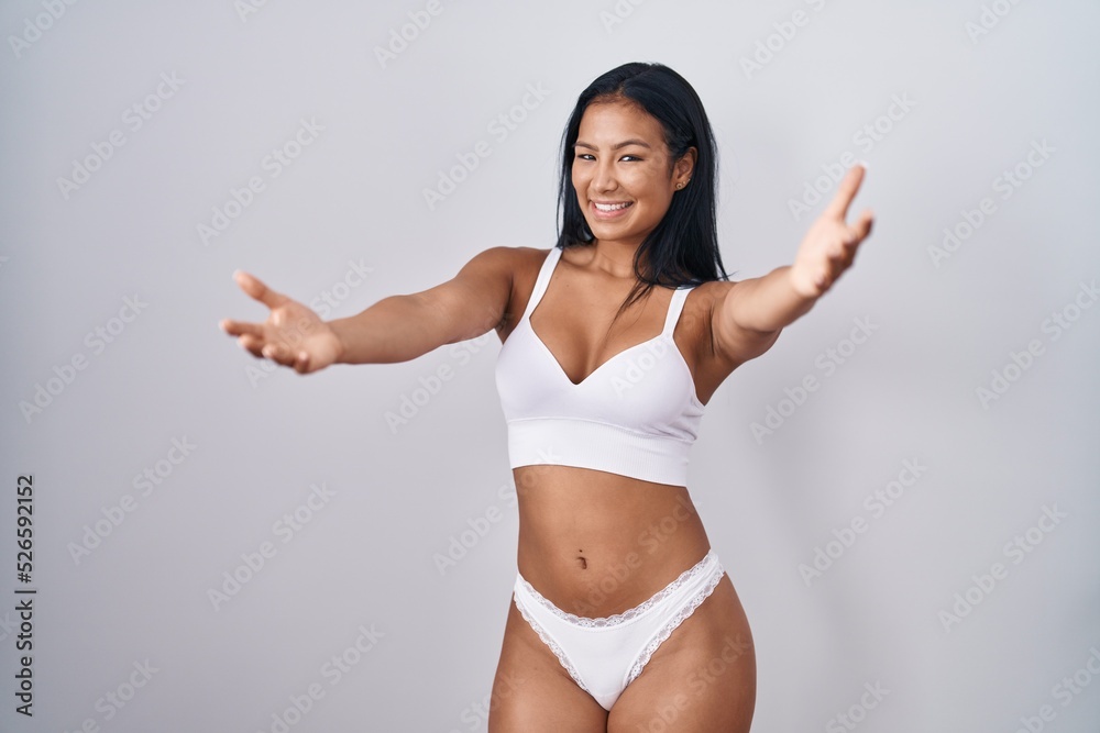 Hispanic woman wearing lingerie looking at the camera smiling with open arms for hug. cheerful expression embracing happiness. Hispanic woman wearing lingerie looking at the camera smiling with open arms for hug. cheerful expression embracing happiness.