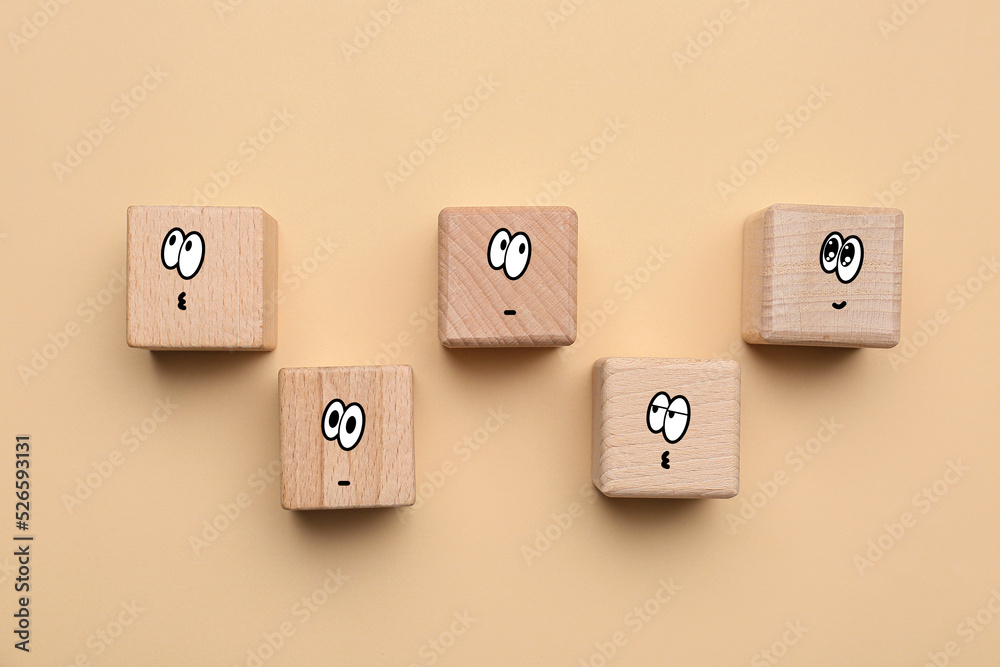 Wooden cubes with different drawn emoticons on beige background Wooden cubes with different drawn emoticons on beige background