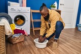 Young african american man cleaning cloth on cube with water at laundry room