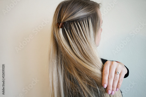Hair extensions procedure. Hairdresser does hair extensions to young girl, blonde in a beauty salon. 