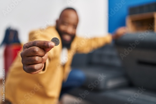 Young african american man holding coin at home photo