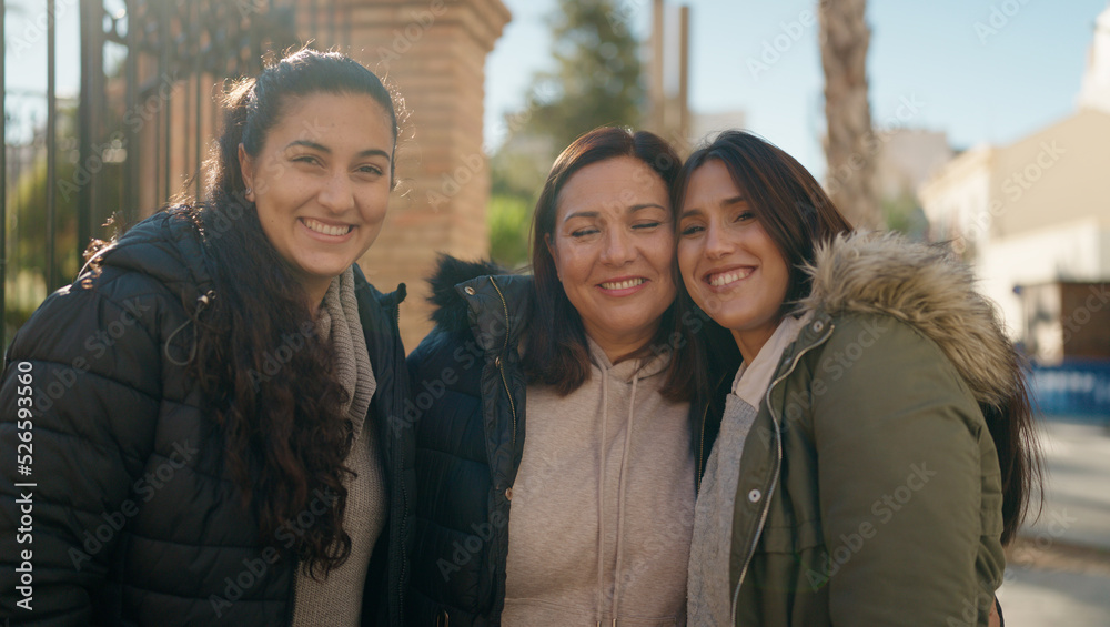 Mother and daugthers smiling confident hugging each other at street