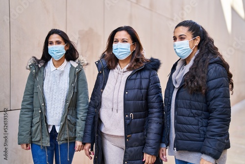 Three woman mother and daughters wearing medical mask standing together at street