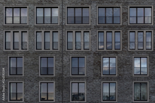 fragment of facade of building with windows. Facing with black brick. Two- and three-leaf windows on gray brick facade. Architectural background