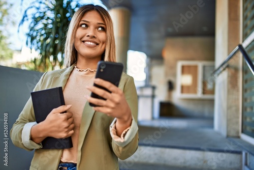 Young latin woman smiling confident using smartphone at street