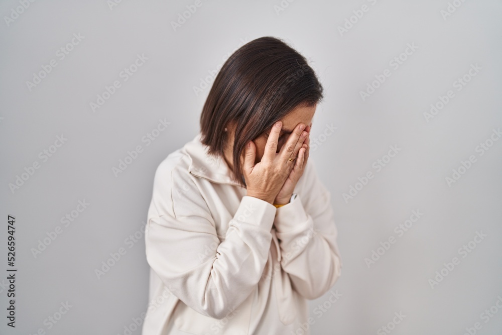 Middle age hispanic woman standing over isolated background with sad expression covering face with hands while crying. depression concept. Middle age hispanic woman standing over isolated background with sad expression covering face with hands while crying. depression concept.
