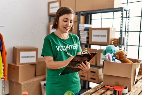 Middle age hispanic woman checking donations on checklist at donations stand