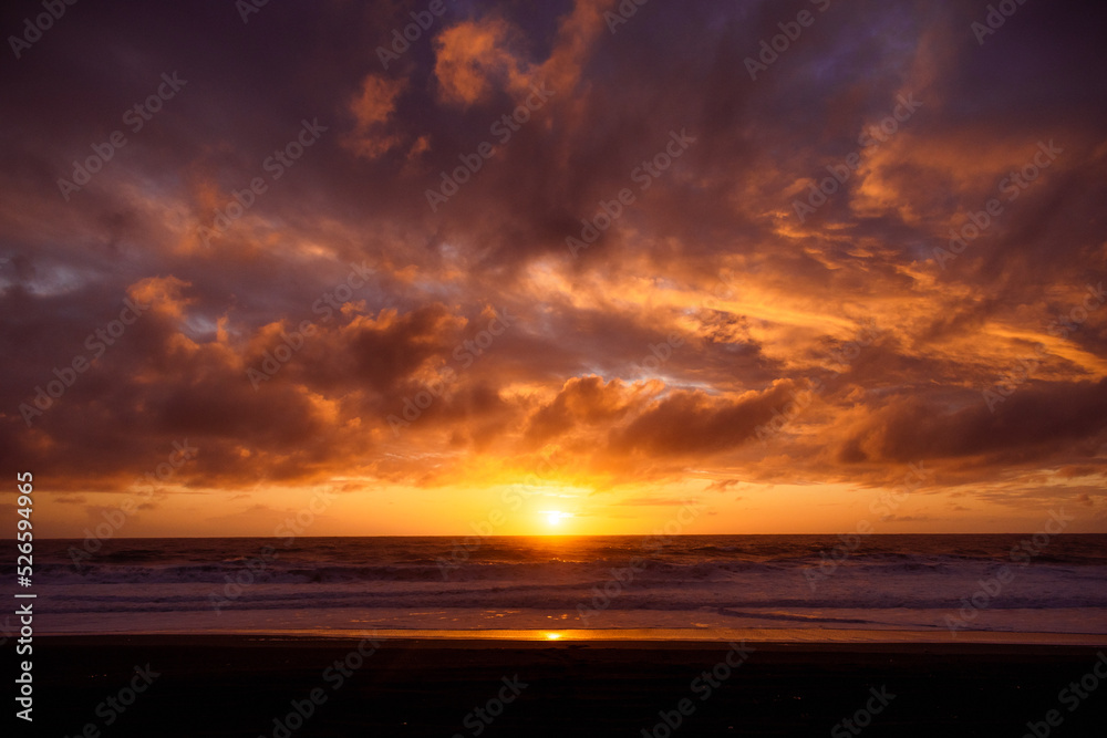 Paisaje de atardecer en la playa con ocaso en el mar y nubes iluminadas por el sol