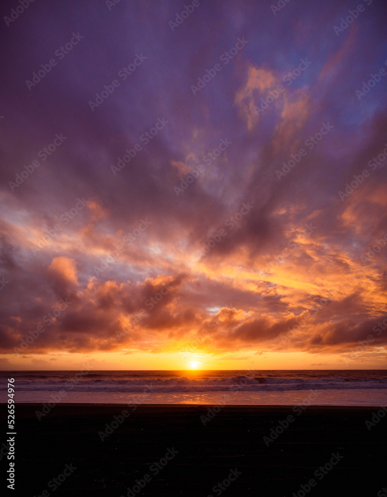 Paisaje de atardecer en la playa con ocaso en el mar y nubes iluminadas por el sol