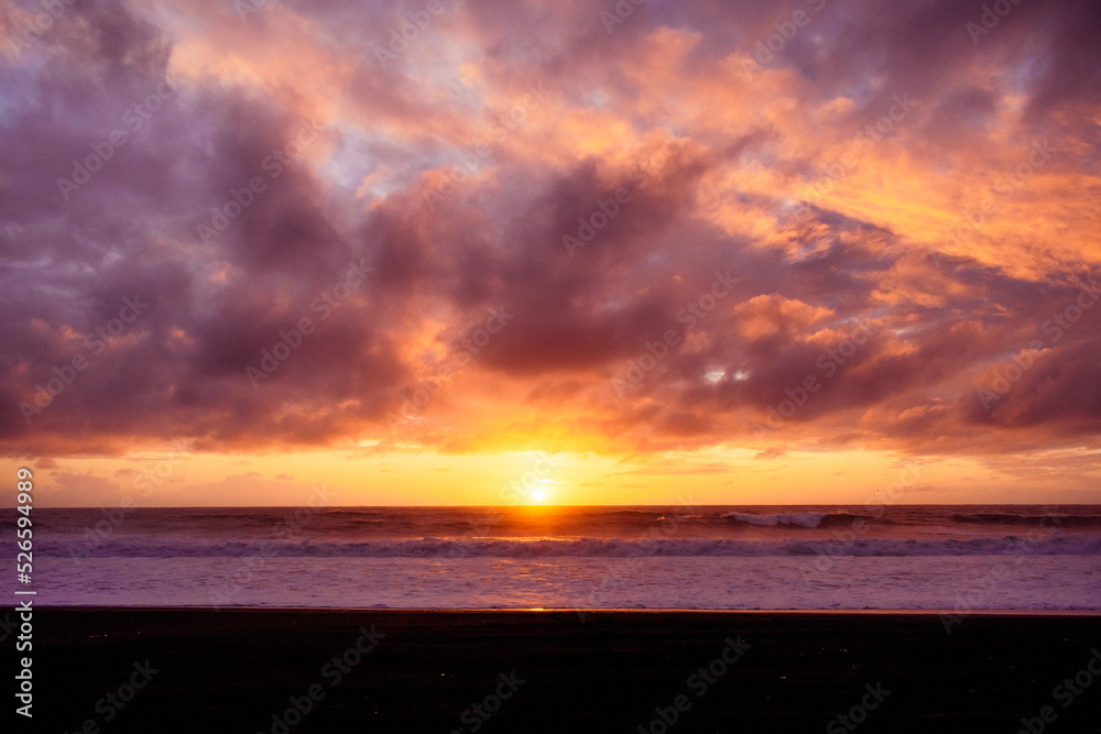 Paisaje de atardecer en la playa con ocaso en el mar y nubes iluminadas por el sol