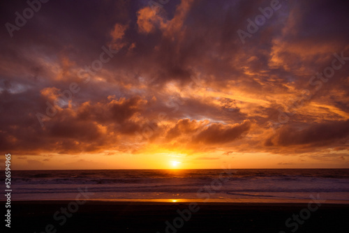 Paisaje de atardecer en la playa con ocaso en el mar y nubes iluminadas por el sol