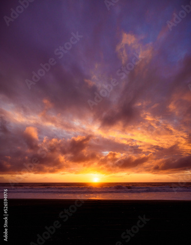 Paisaje de atardecer en la playa con ocaso en el mar y nubes iluminadas por el sol