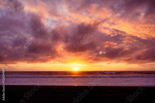 Paisaje de atardecer en la playa con ocaso en el mar y nubes iluminadas por el sol