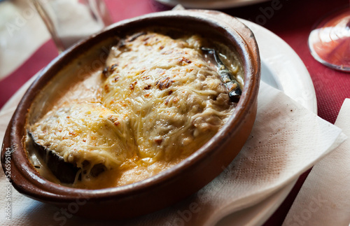 Spanish cuisine. Delicious meat stuffed eggplants topped with grated cheese served in clayware