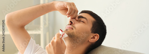 Young man with nosebleed at home photo