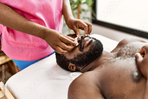African american man reciving facial treatment at beauty center.