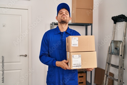 Young hispanic man working on moving service holding boxes looking at the camera blowing a kiss being lovely and sexy. love expression. © Krakenimages.com