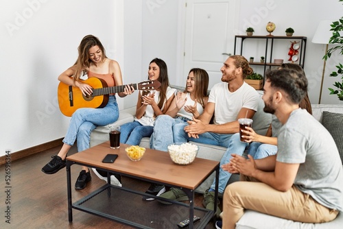 Group of young friends having party playing spanish guitar at home.