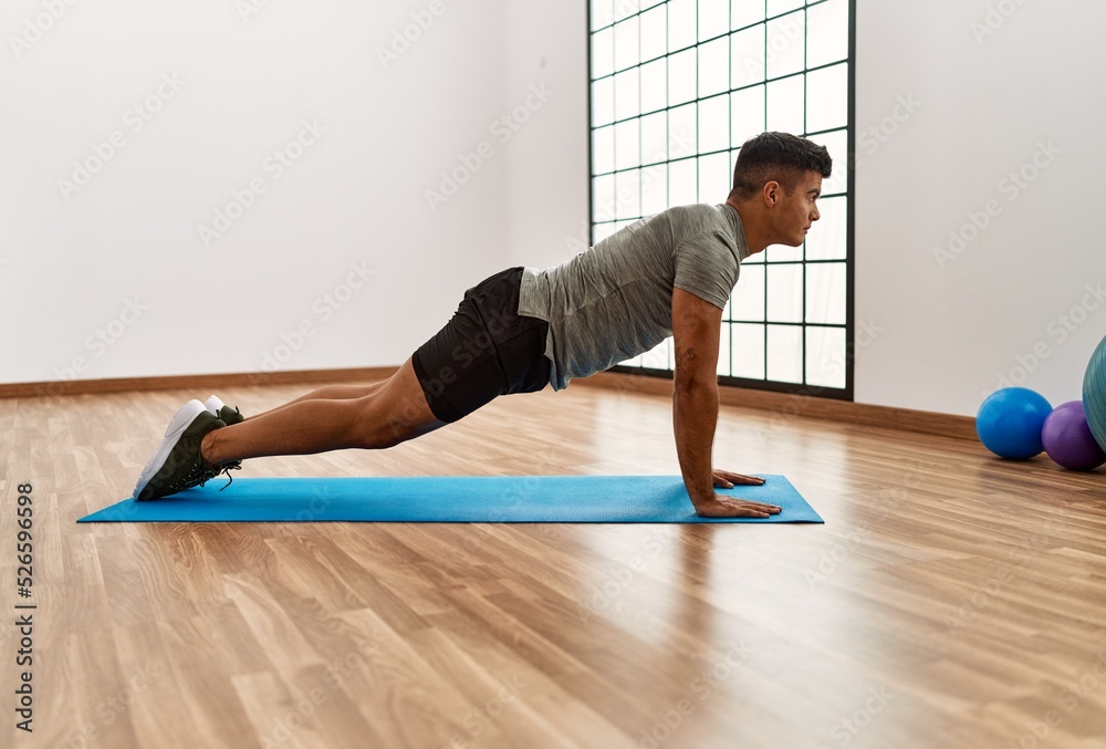 Young hispanic man stretching at sport center