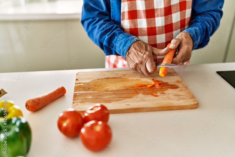 Senior man cutting carrot at kitchen Senior man cutting carrot at kitchen