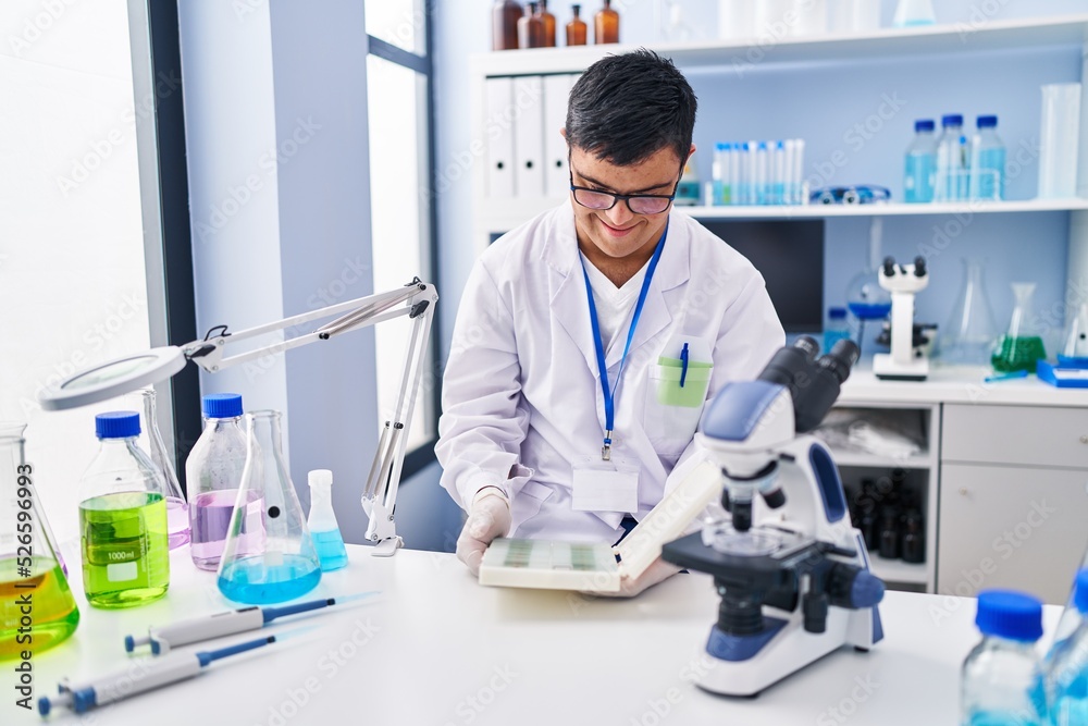 Down syndrome man wearing scientist uniform working at laboratory Down syndrome man wearing scientist uniform working at laboratory