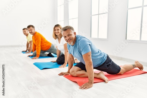 Group of middle age people training yoga at sport center.