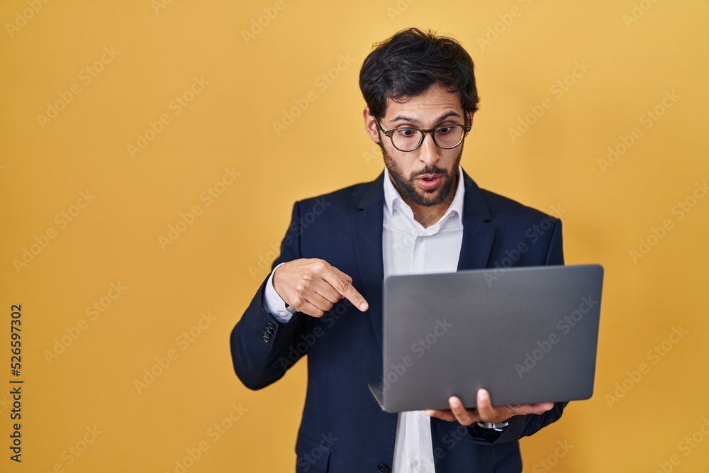 Handsome latin man working using computer laptop pointing down with fingers showing advertisement, surprised face and open mouth Handsome latin man working using computer laptop pointing down with fingers showing advertisement, surprised face and open mouth