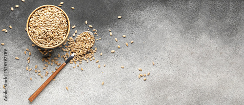 Bowl and spoon with peeled sunflower seeds on grey background with space for text