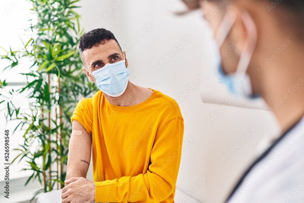 Fototapeta premium Two man doctor and patient put band aid on arm at clinic