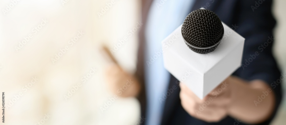 Fototapeta premium Female journalist with microphone in office, closeup