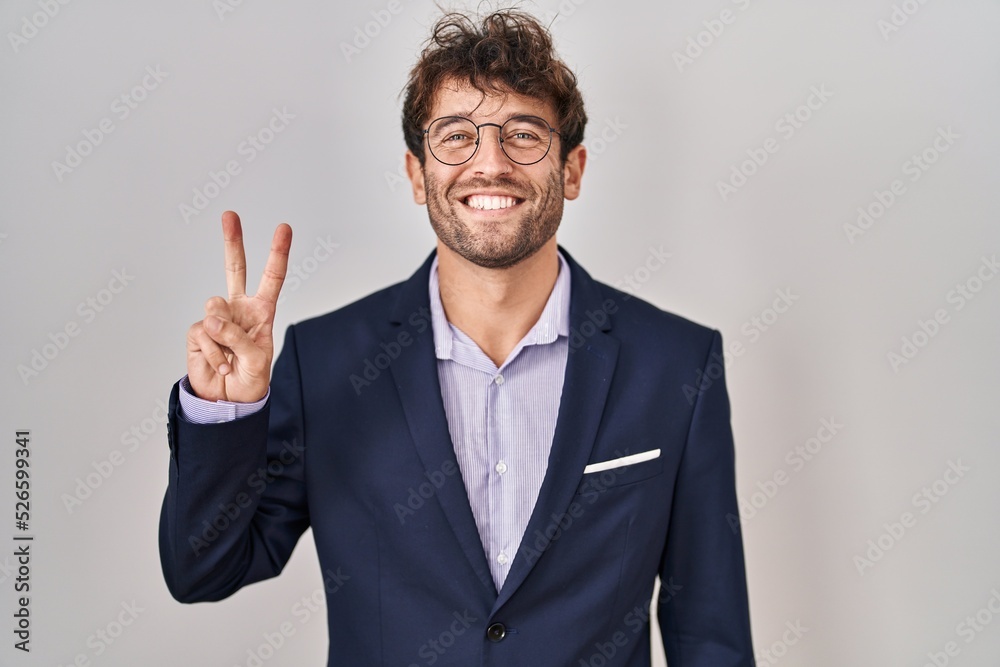 Hispanic business man wearing glasses showing and pointing up with fingers number two while smiling confident and happy. Hispanic business man wearing glasses showing and pointing up with fingers number two while smiling confident and happy.