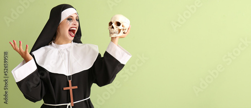 Woman dressed for Halloween as nun with skull on green background with space for text photo