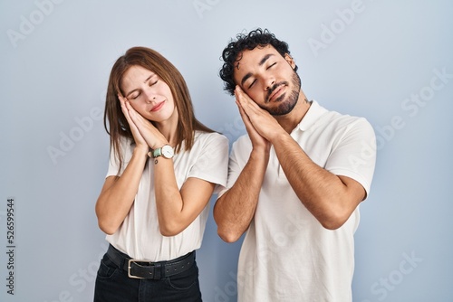 Young couple wearing casual clothes standing together sleeping tired dreaming and posing with hands together while smiling with closed eyes.