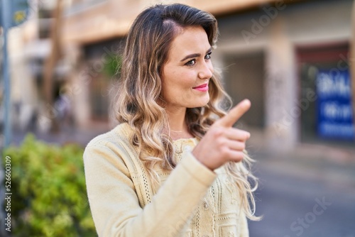 Young woman smiling confident pointing with finger at street