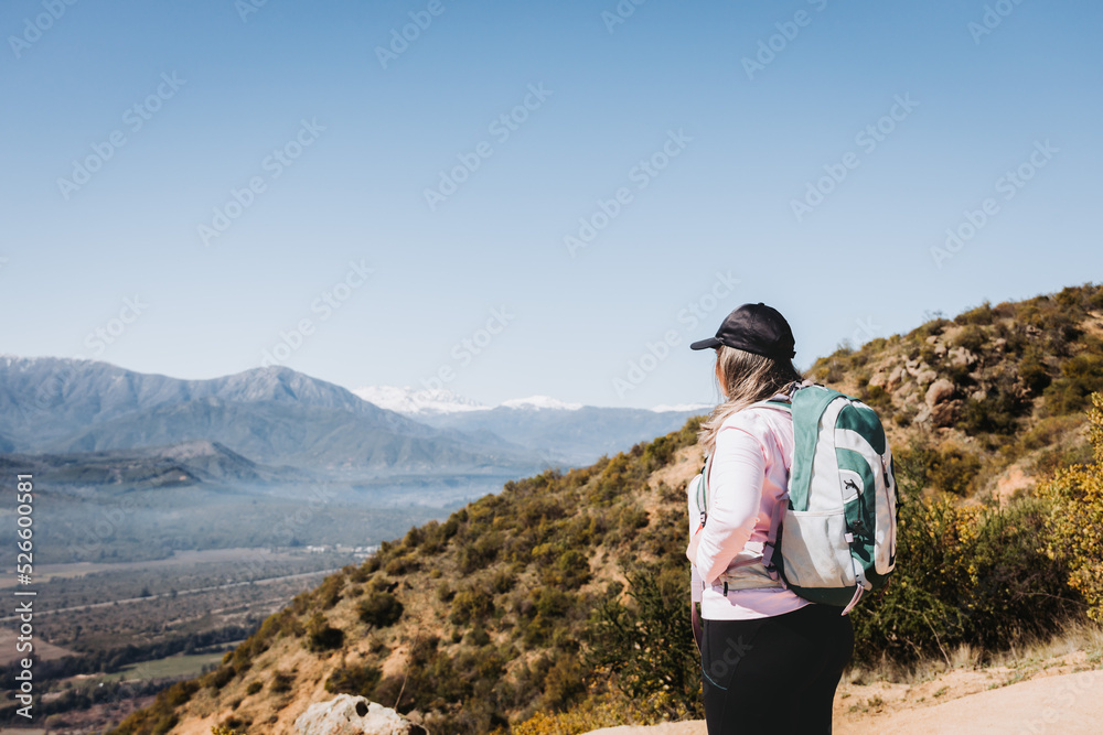 Rear view young latin plus size woman with backpack on, contemplating view from the top of a hill