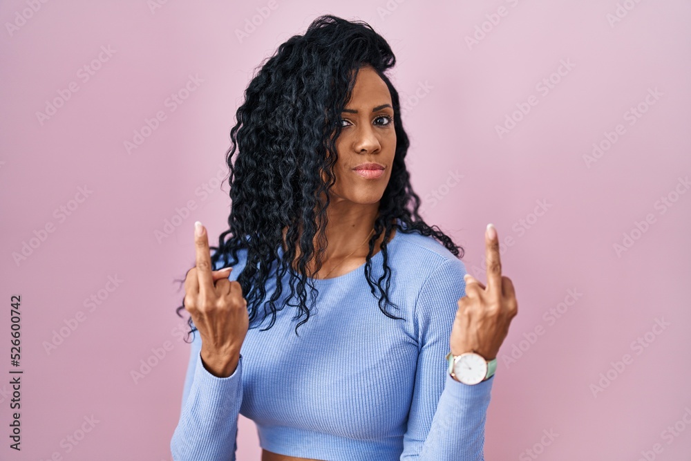 Middle age hispanic woman standing over pink background showing middle finger doing fuck you bad expression, provocation and rude attitude. screaming excited Middle age hispanic woman standing over pink background showing middle finger doing fuck you bad expression, provocation and rude attitude. screaming excited